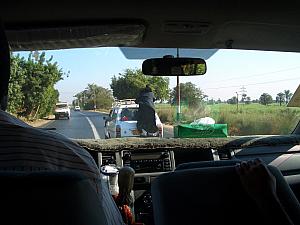 Yes, that's a man standing on the back bumper of a station wagon on the road!