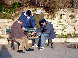 Some young men playing chess on a bench.