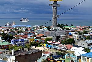 Punta Arenas, Chile, on a hillside at the edge of town. Our ship in the background; signs pointing the location and  distance to faraway cities in the foreground.