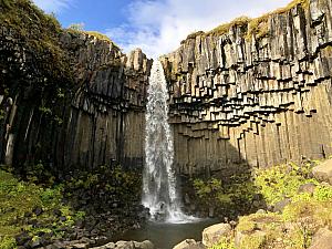 Svartifoss waterfall in Skaftafell in Vatnajkull National Park. The waterfall is bordered on both sides by tall black basalt columns. The hexagonal columns form inside a lava flow which then cools extremely slowly, giving rise to crystallization.